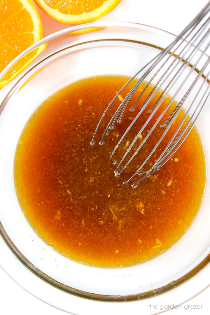 Whisking together a citrus sauce in a small glass bowl