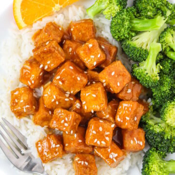 Orange tofu with white rice and steamed broccoli on a white plate