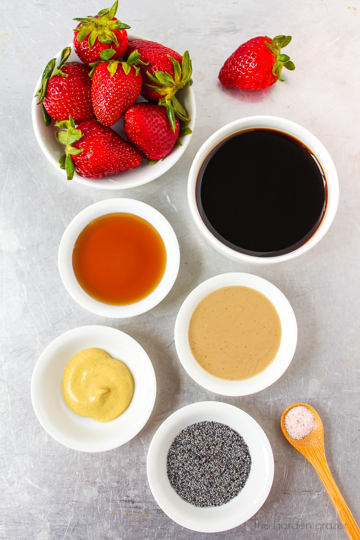 Vinegar, fresh berries, Dijon mustard, maple syrup, tahini, and poppy seed ingredients laid out on a metal tray