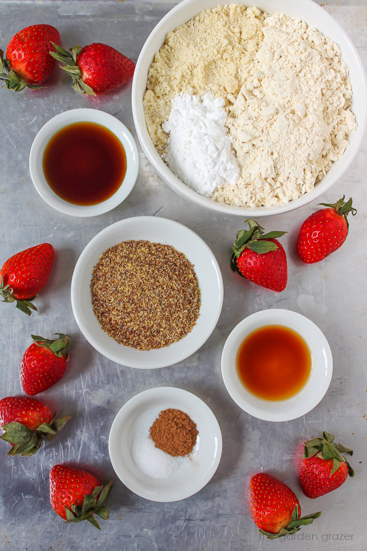 Flour, flax, berries, syrup, and vanilla ingredients set out in bowls