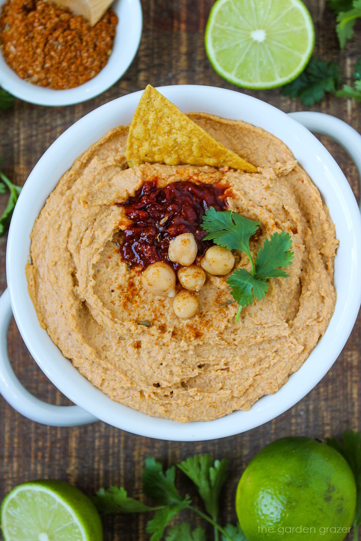 Close up view of chipotle taco hummus in a white bowl with garnish