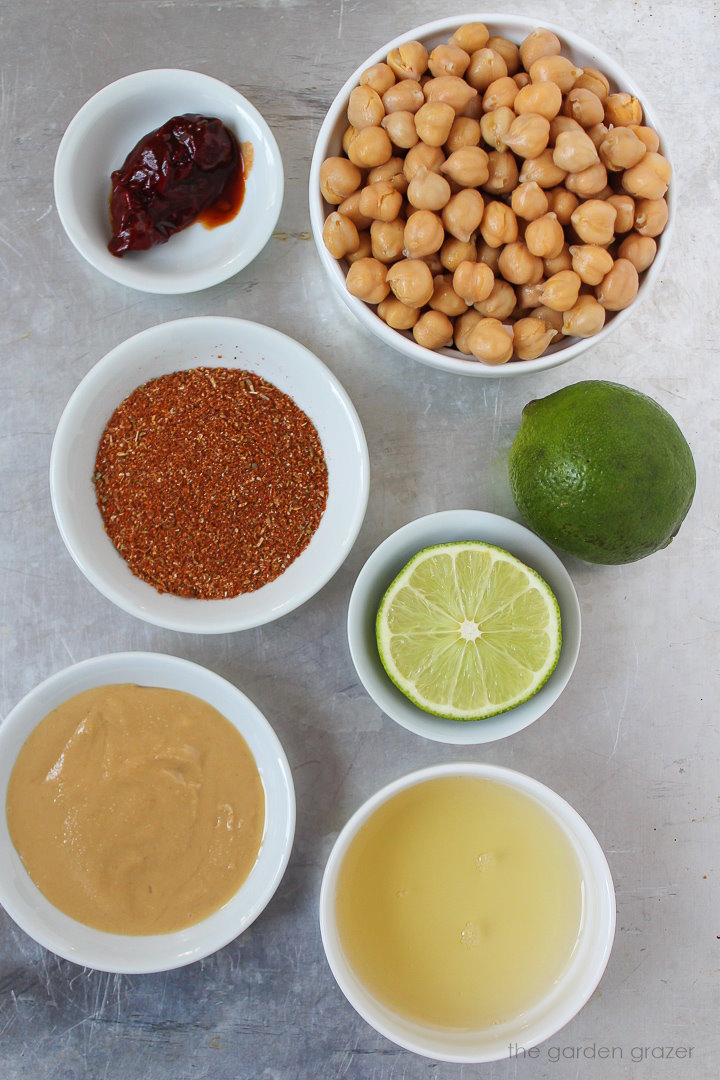 Chickpeas, taco seasoning, limes, and tahini ingredients set out in white bowls