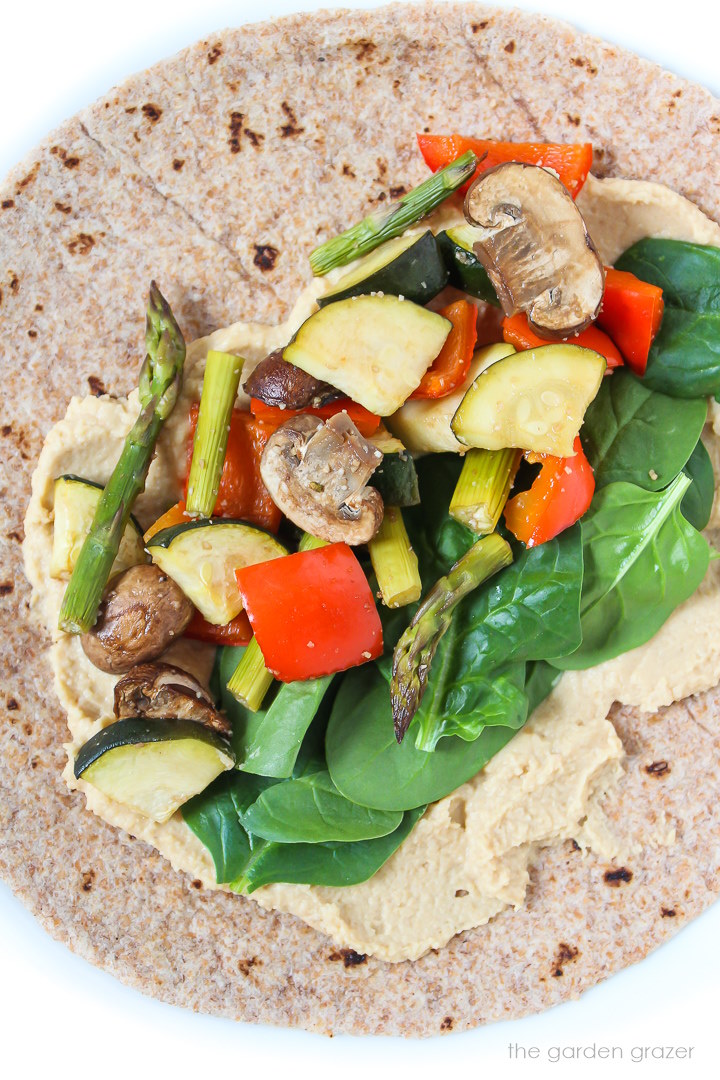Overhead view of an open-faced roasted veggie hummus wrap