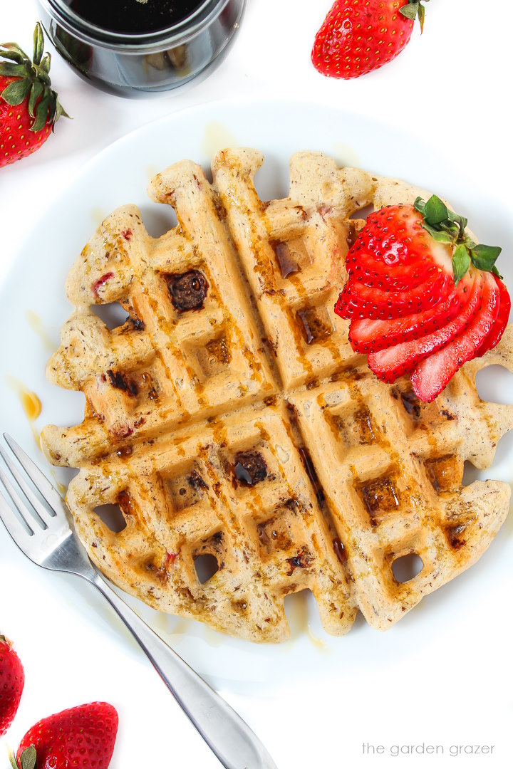 Vegan gluten-free strawberry Belgian waffles on a white plate with fork