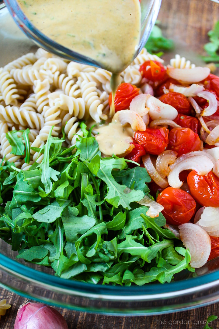 Homemade Italian dressing being poured over ingredients in a large glass bowl before mixing together