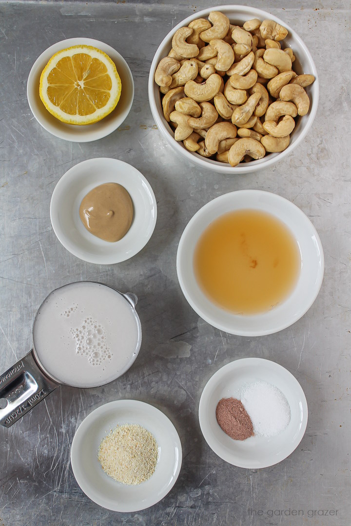 Nuts, lemon, mustard, vinegar, milk, and spice ingredients laid out on a metal tray