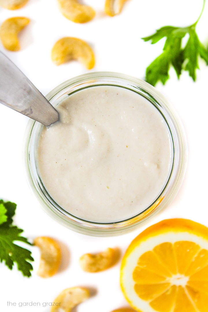 Overhead view of vegan cashew mayo in a small glass jar with serving spoon