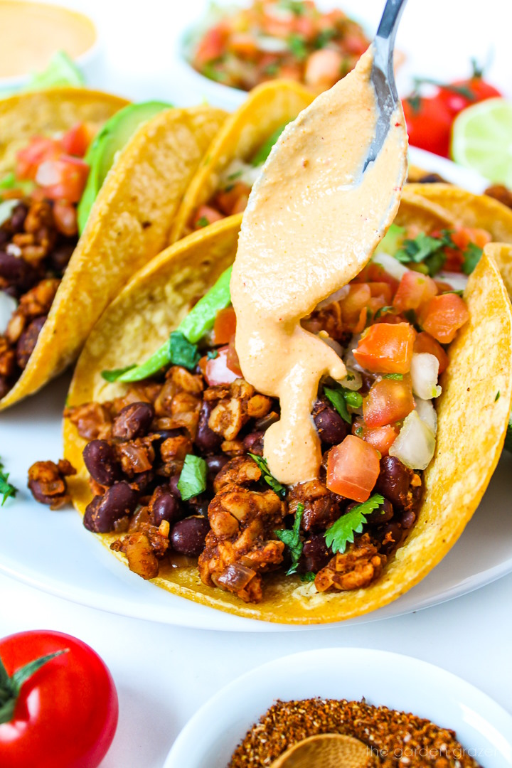 Chipotle crema being spooned on top of vegan tacos