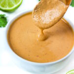 Wooden spoon lifting up vegan chipotle crema from a small white bowl