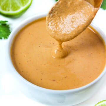 Wooden spoon lifting up vegan chipotle crema from a small white bowl