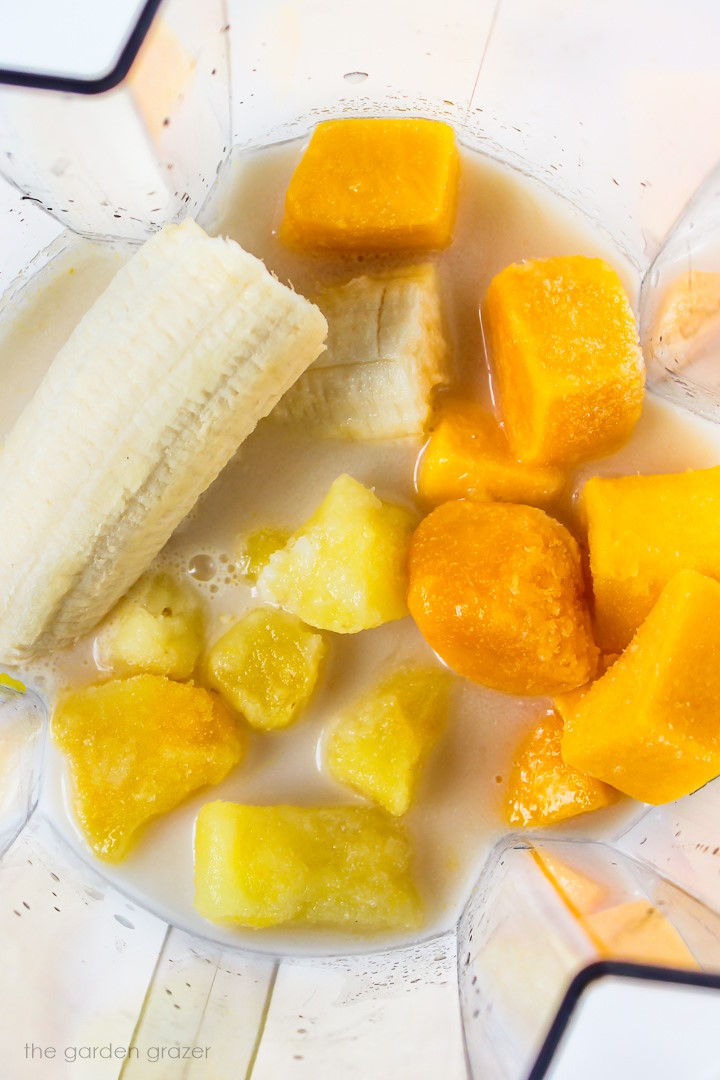 Overhead view of smoothie ingredients in a blender before blending