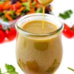 Maple Dijon dressing in a small glass jar with serving spoon