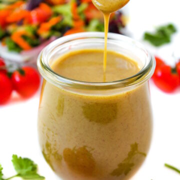 Maple Dijon dressing in a small glass jar with serving spoon