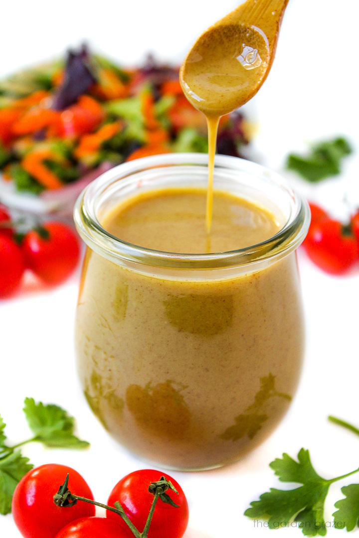 Maple Dijon dressing in a small glass jar with serving spoon