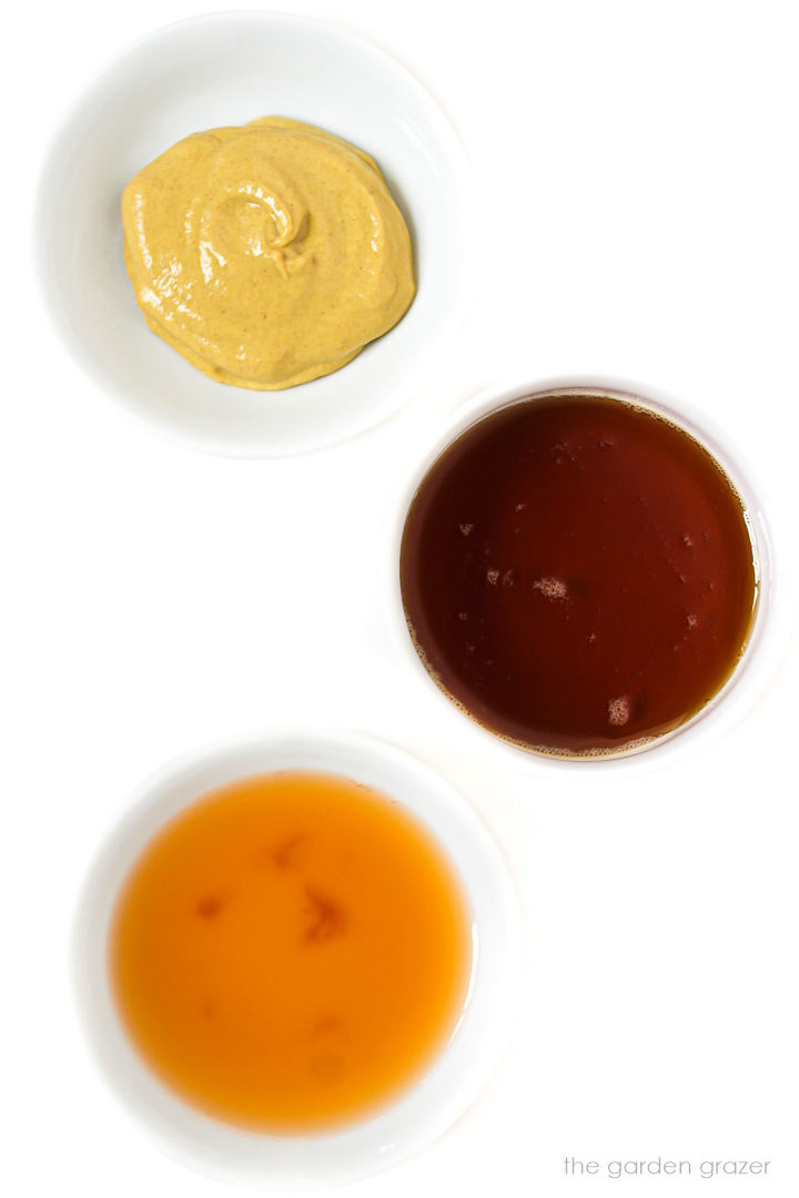 Mustard, vinegar, and syrup ingredients laid out in white bowls