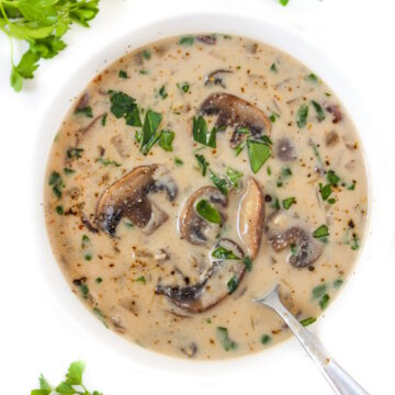 Overhead view of vegan mushroom soup in a white bowl with spoon