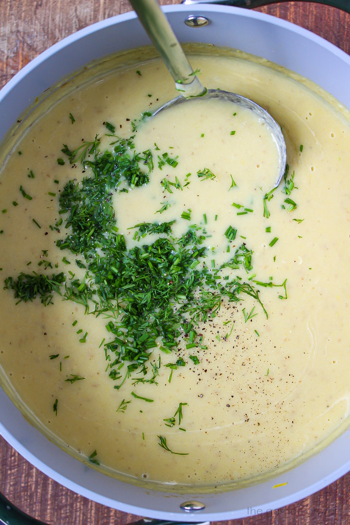 Overhead view of ladle scooping up vegan potato leek soup as it cooks in a stockpot