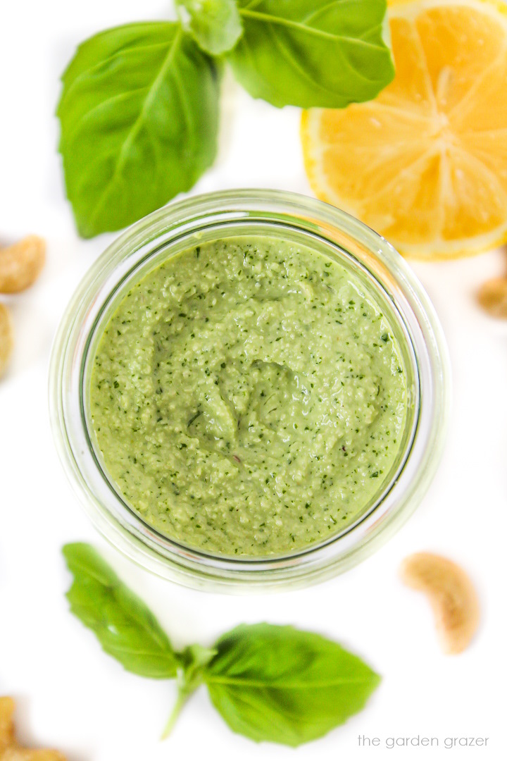 Vegan cashew pesto in a small jar with fresh basil on the side