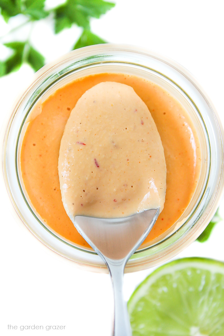 Spoon holding cashew chipotle crema over a glass jar