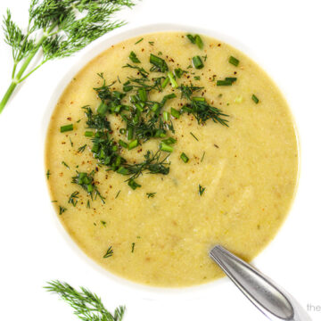 Vegan leek and potato soup in a bowl with white background