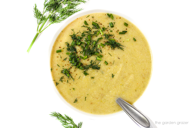 Vegan leek and potato soup in a bowl with white background