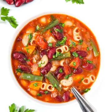 Vegan minestrone soup in a white bowl garnished with fresh parsley