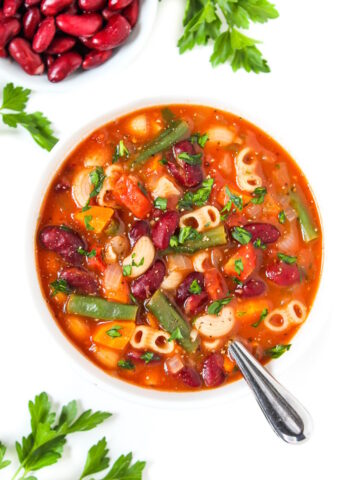 Vegan minestrone soup in a white bowl garnished with fresh parsley