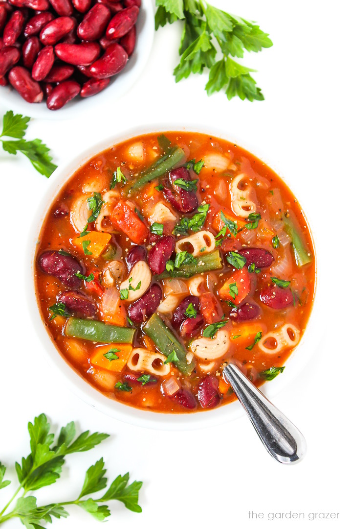 Vegan minestrone soup in a white bowl garnished with fresh parsley