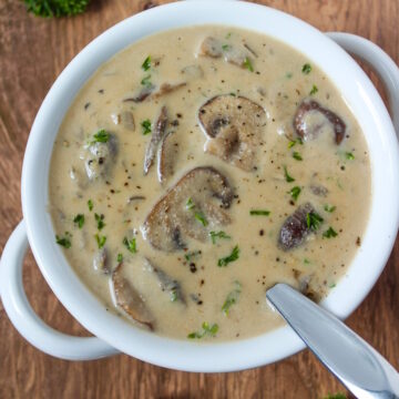 Vegan cream of mushroom soup in a white serving bowl garnished with parsley