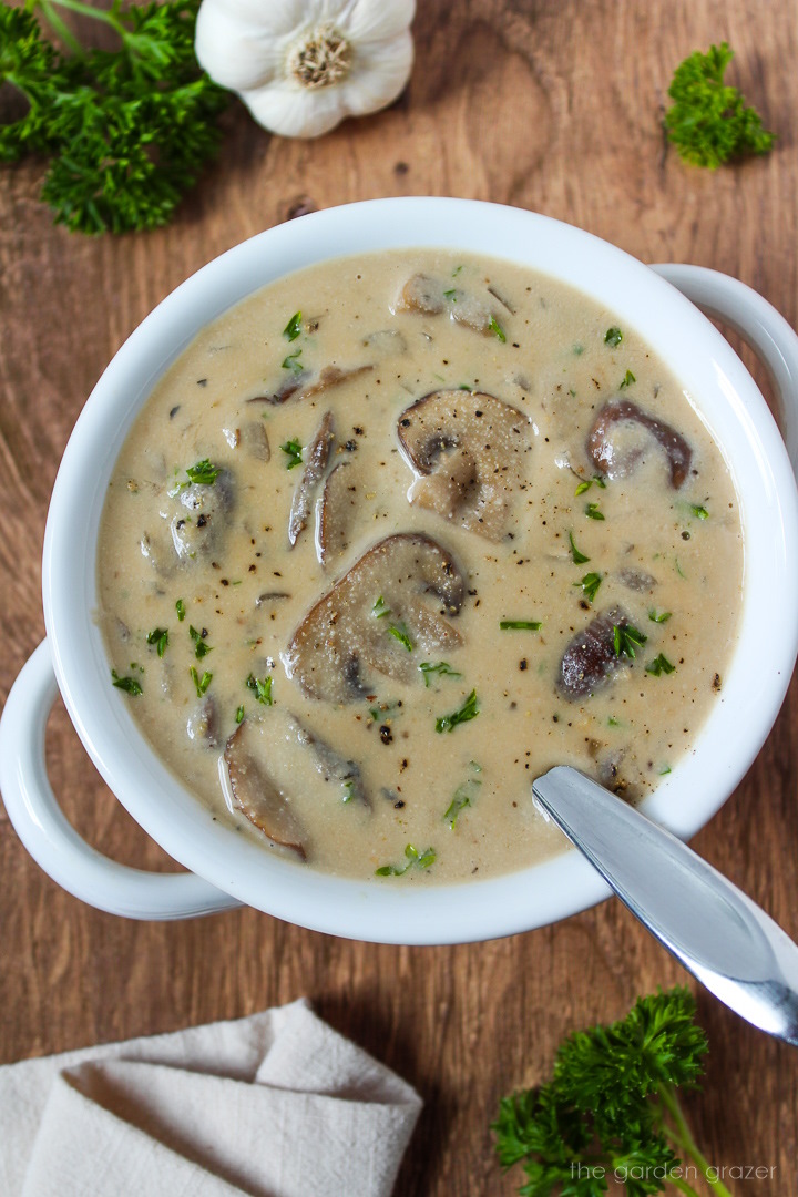 Vegan cream of mushroom soup in a white serving bowl garnished with parsley