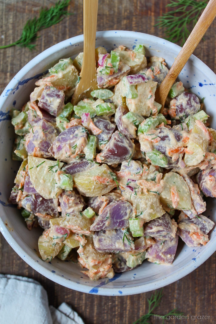Overhead view of dairy-free potato salad with fresh dill in a white bowl