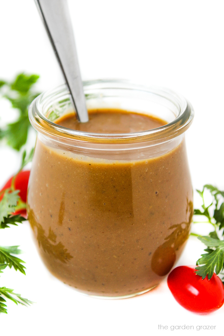 Oil-free creamy balsamic dressing with hummus in a small glass jar with spoon