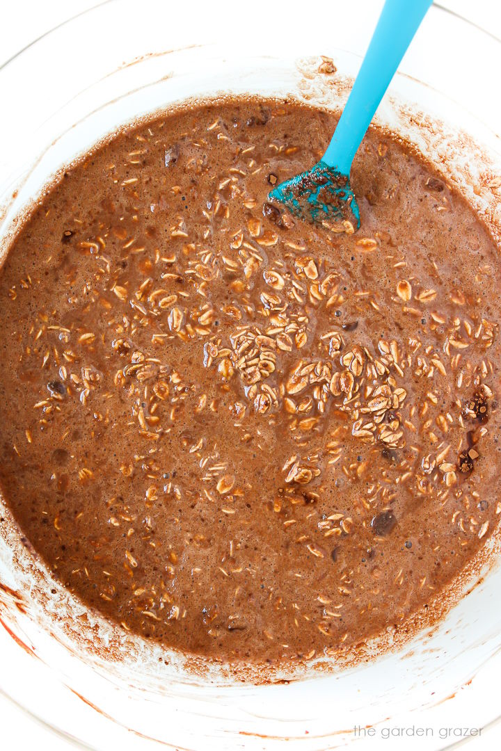 Brownie baked oatmeal batter mixed together in a large glass bowl with blue spatula