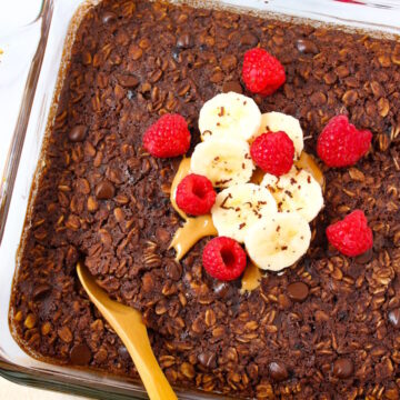 Vegan brownie baked oatmeal in a glass baking dish with serving spoon