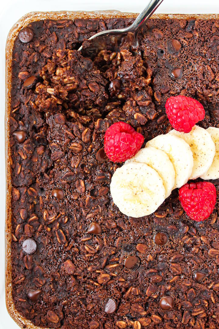 Close up view of brownie baked oatmeal in a glass dish with serving spoon