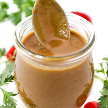 Creamy balsamic dressing in a small glass jar with serving spoon