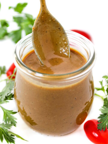 Creamy balsamic dressing in a small glass jar with serving spoon