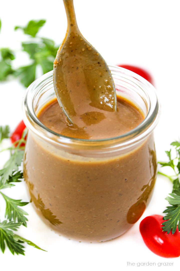 Creamy balsamic dressing in a small glass jar with serving spoon