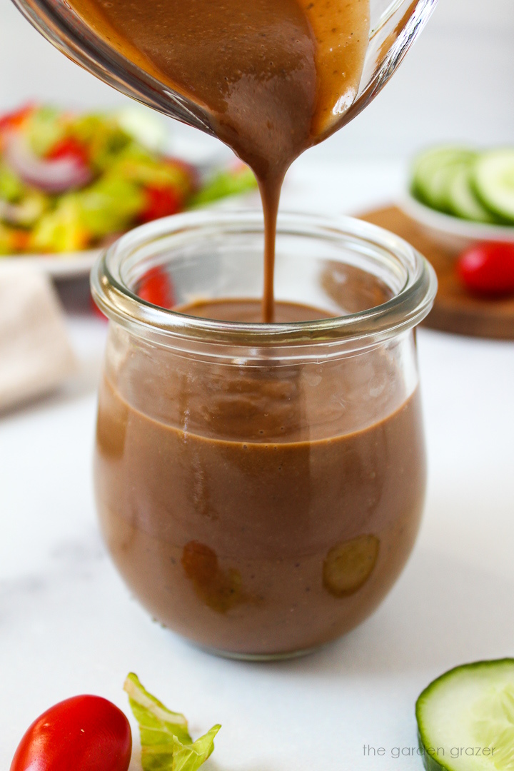 Blended creamy balsamic dressing being poured into a small jar