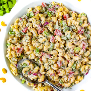 Vegan macaroni salad in a white bowl with serving spoon