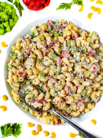 Vegan macaroni salad in a white bowl with serving spoon
