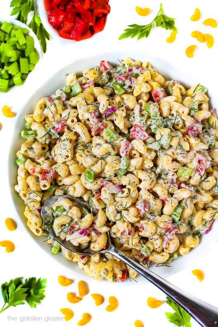 Vegan macaroni salad in a white bowl with serving spoon