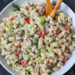 Vegan macaroni salad with creamy dressing in a white serving bowl with wooden spoons