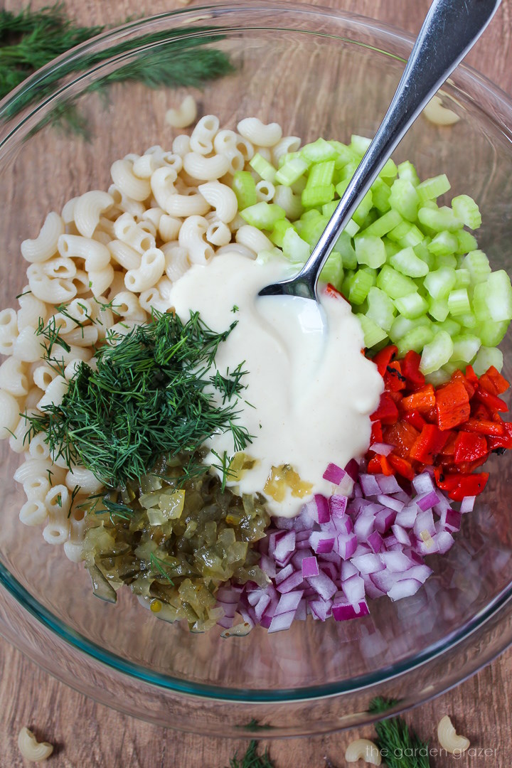 Overhead view of preparing ingredients and dressing in a large glass bowl before mixing together