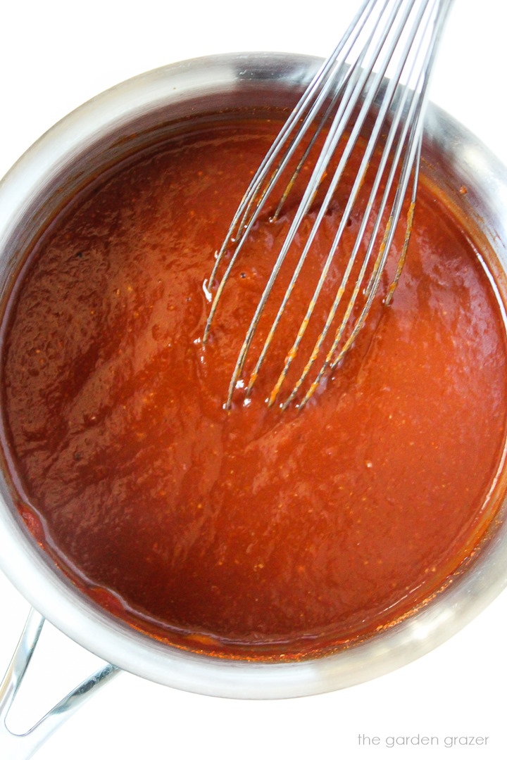 Overhead view of barbecue sauce cooking in a pan with metal whisk