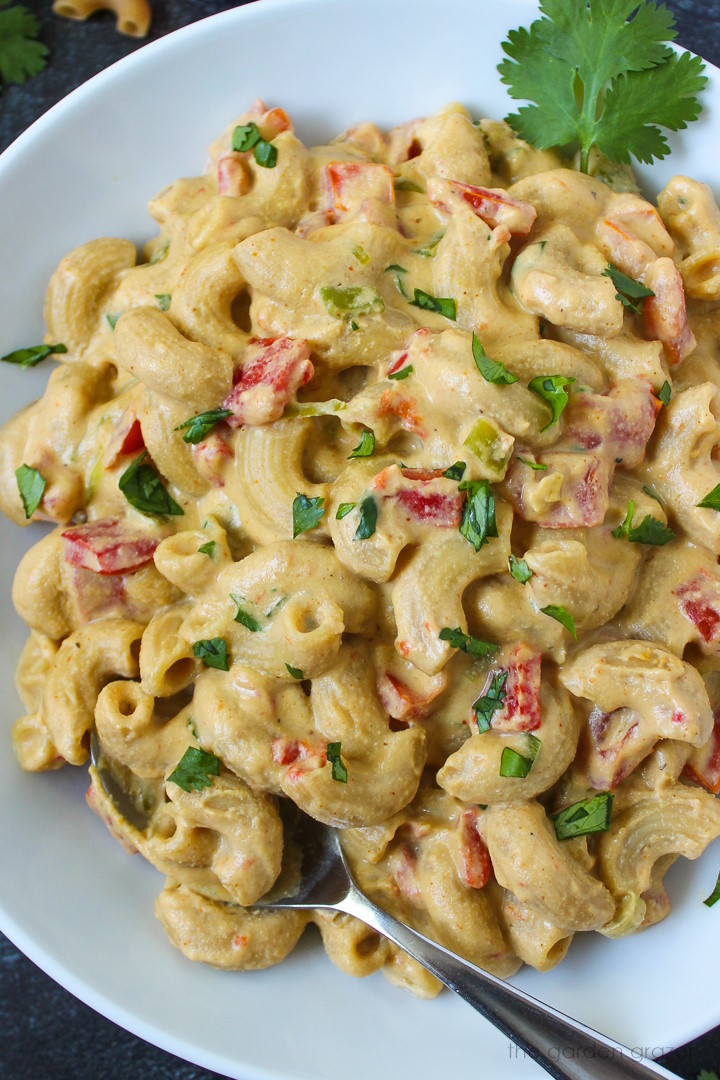 Close up view of vegan Mexican mac and cheese served in a white bowl with fresh cilantro