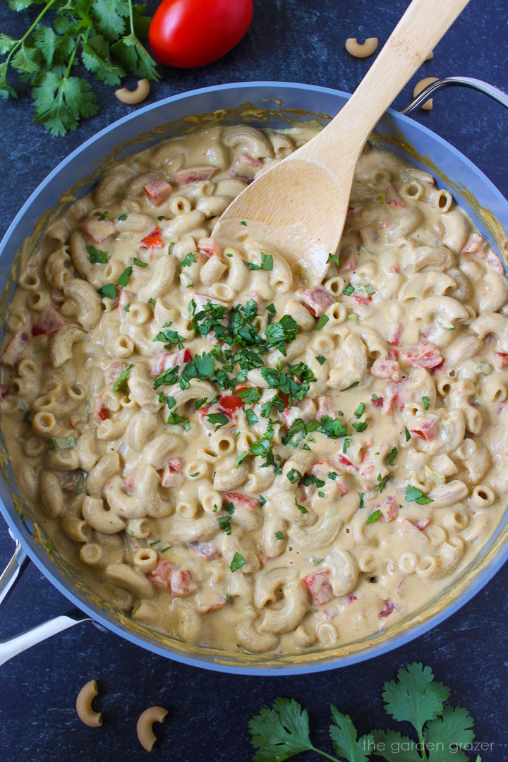 Mexican mac and cheese cooking in a large pan with stirring spoon