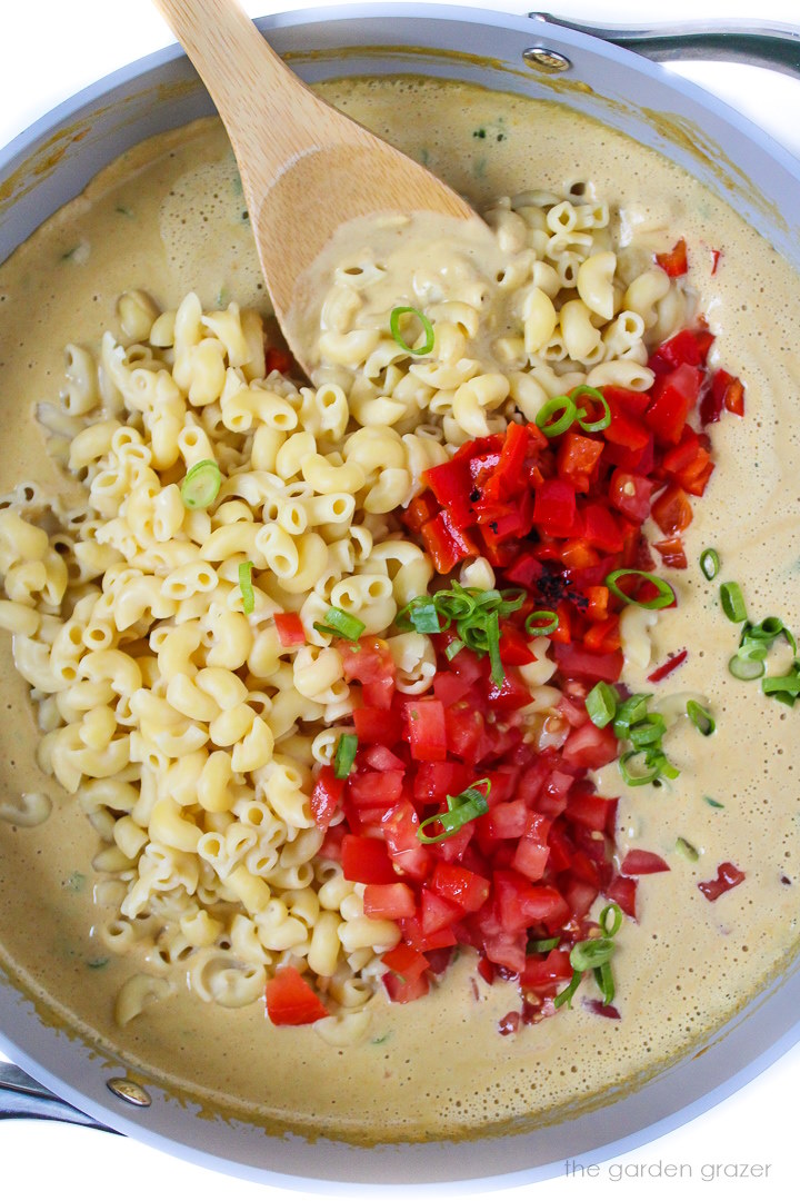 Combining cheese sauce, macaroni noodles, and vegetables in a large skillet