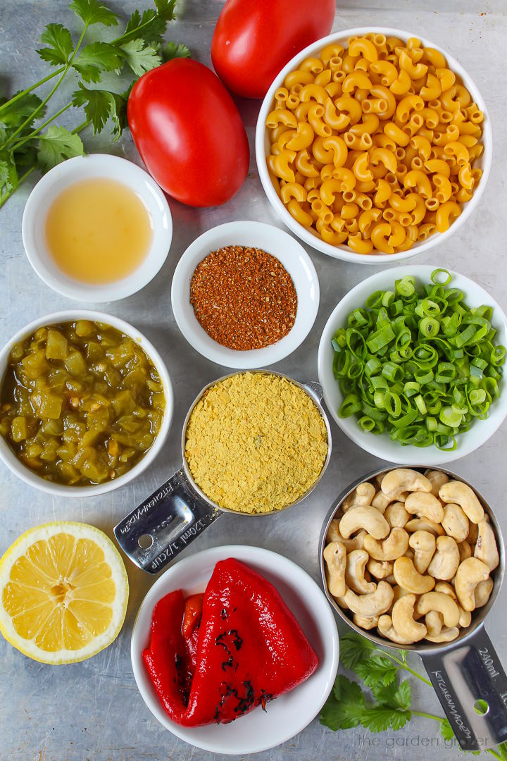 Pasta, tomato, cashews, nutritional yeast, green onions, and spice ingredients laid out on a metal tray