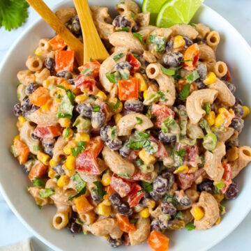Overhead view of vegan Mexican macaroni salad in a white serving bowl with fresh lime slices